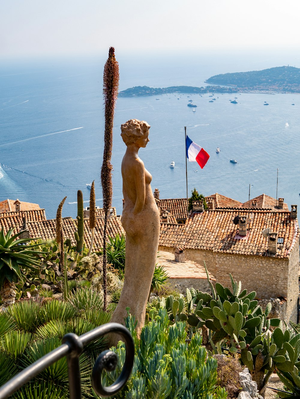 woman brown statue with view of France flag during daytime