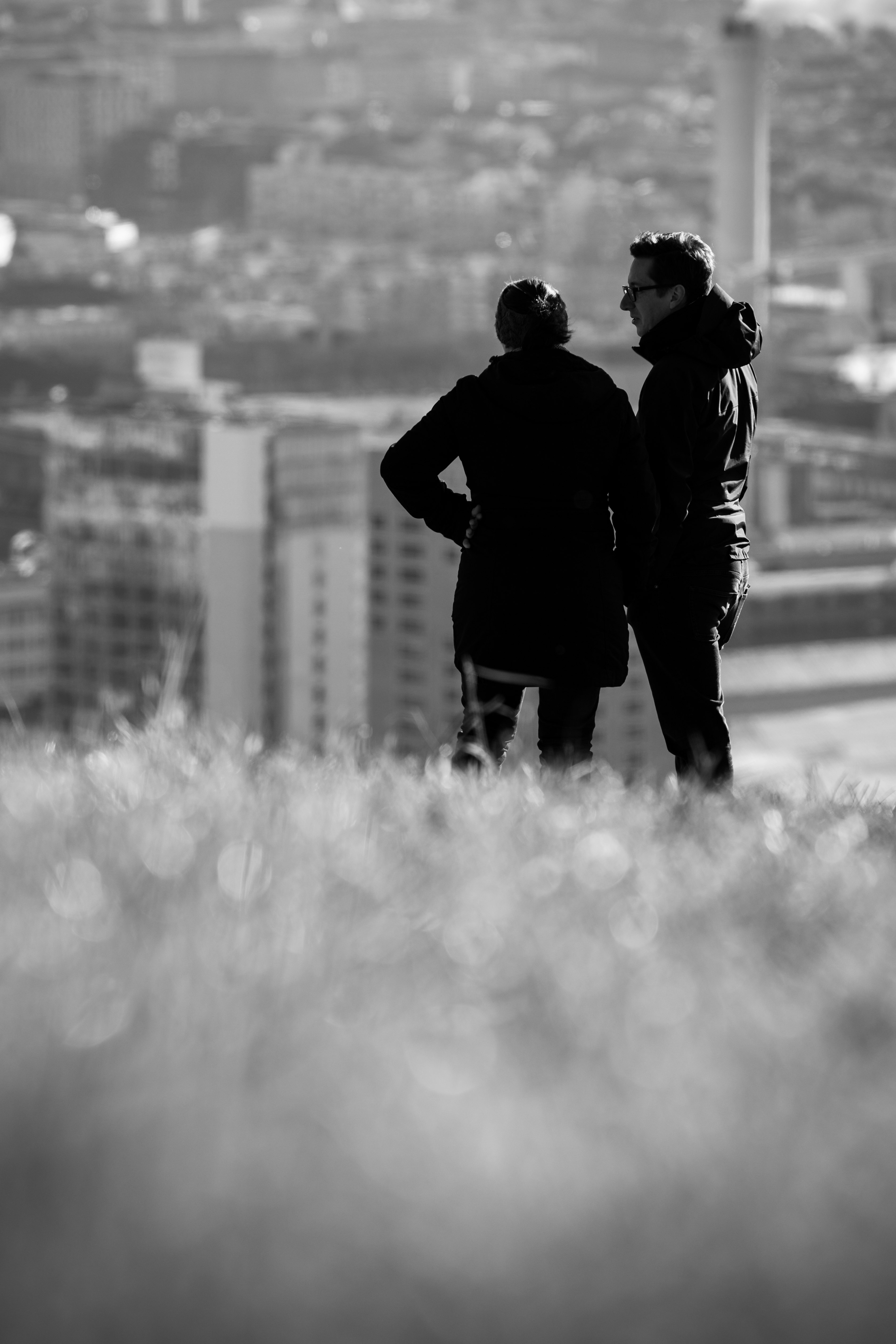 grayscale photo of two people standing on top with view of cityscape