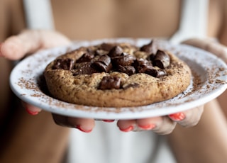 woman holding white saucer with cookie on top