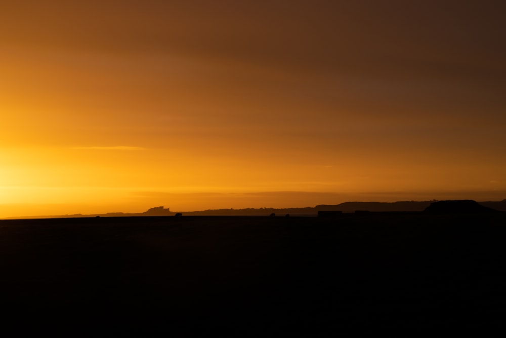 the sun is setting over the horizon of a field