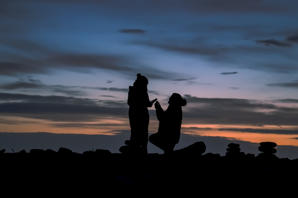 silhouette of man kneeling beside woman during nighttime
