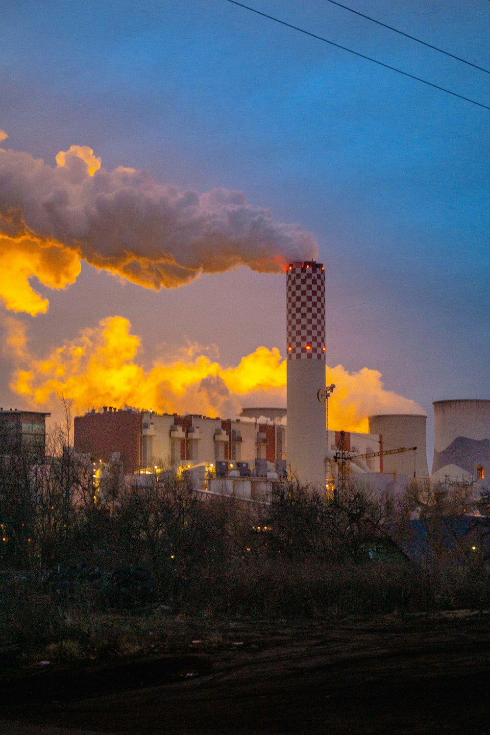 white smoke coming from factory under white and yellow sky