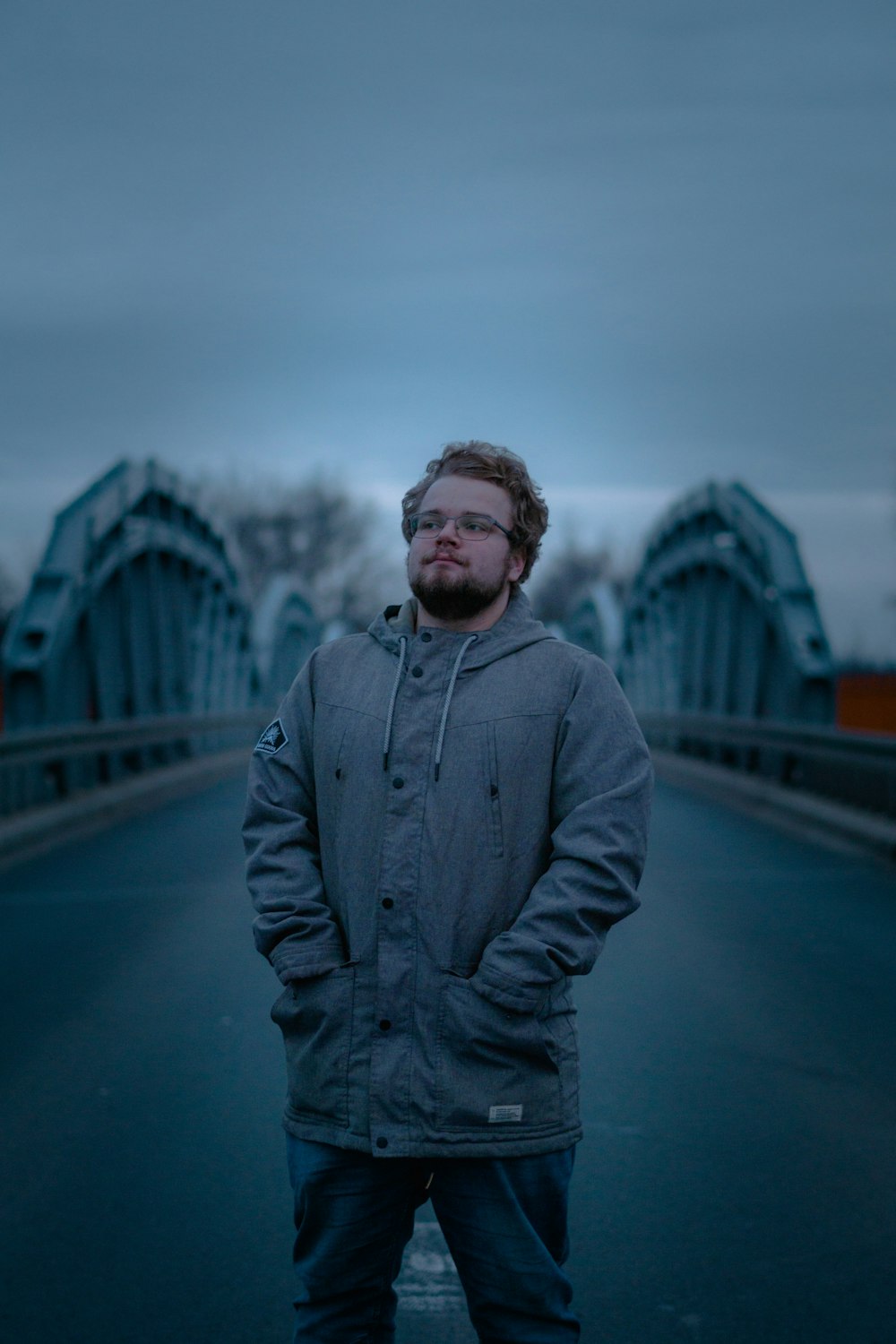 man wearing gray hooded jacket standing on road