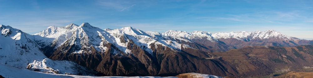 青と白の空の下、雪に覆われた山頂の眺め