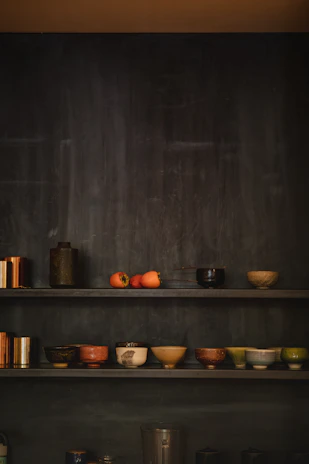 Brightly glazed ceramic bowls stacked with fresh fruit inside a cozy kitchen.