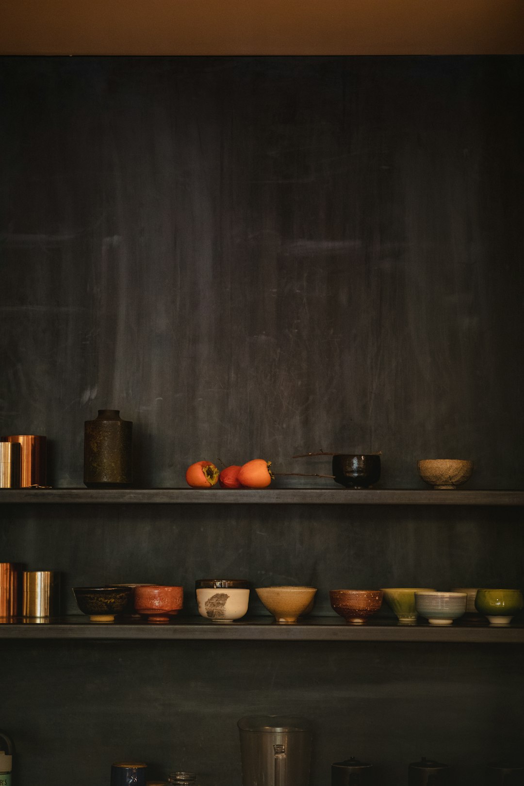 assorted ceramic vases, bowl, and figurines on black wooden shelf