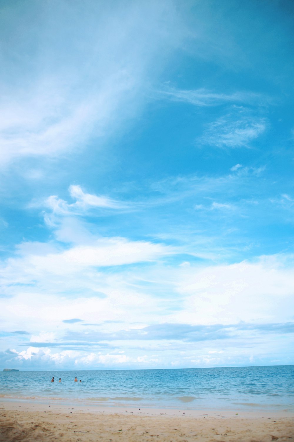 Menschen am Strand unter weißem und blauem Himmel