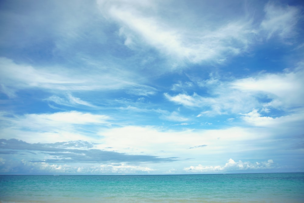 body of water under white clouds during daytime