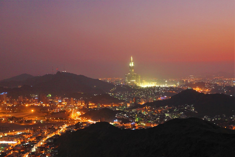 Fotografía aérea de la ciudad con edificios de gran altura que ven la montaña durante la noche