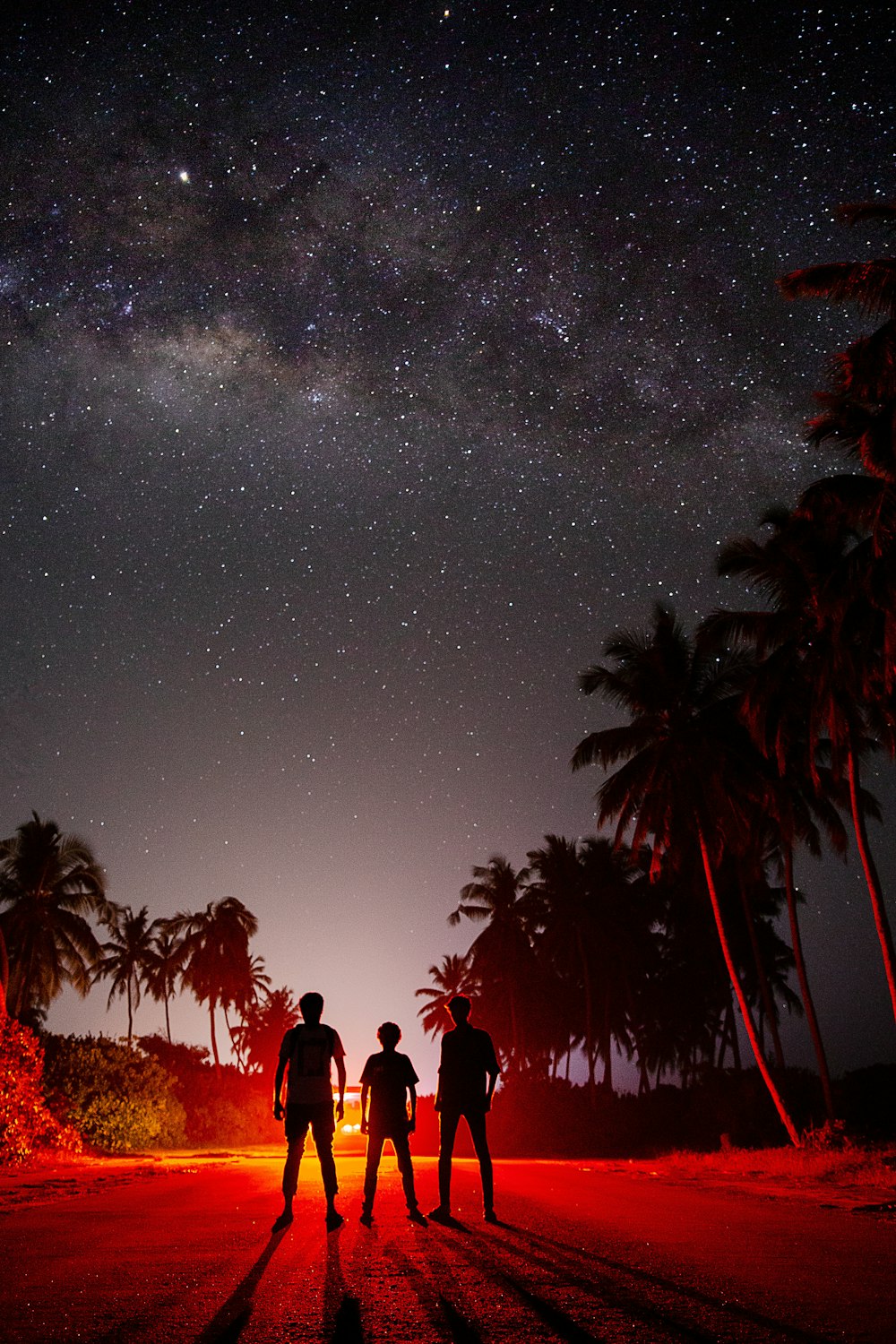 silhouette of three people standing during night time