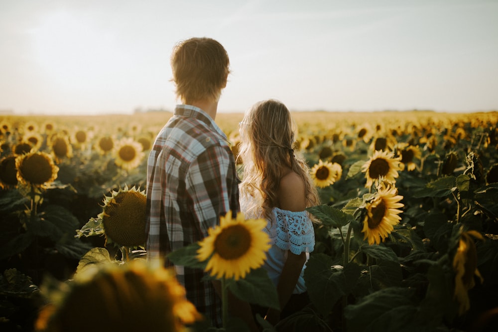 man and woman standing near sunflower field during daytime
