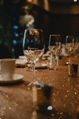 Softly illuminated table setting showcasing elegant glassware and fine cutlery ready for guests.