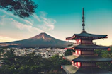 A red pagoda overlooking a city with Mount Fuji in the distance