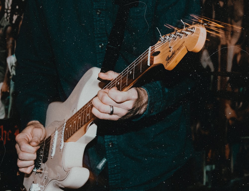 person holding white electric guitar