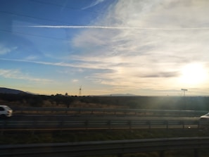 A scenic view of a car on a highway during sunset.
