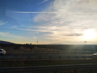A scenic view of a car on a highway during sunset.