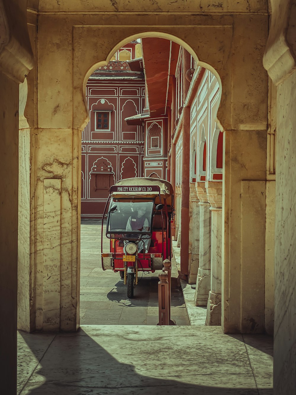 person sitting on parked autorickshaw beside building during day