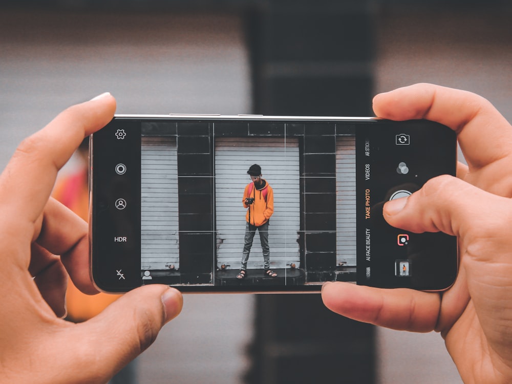 person using smartphone camera viewing standing man