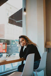 woman leaning on brown wooden table near glass window