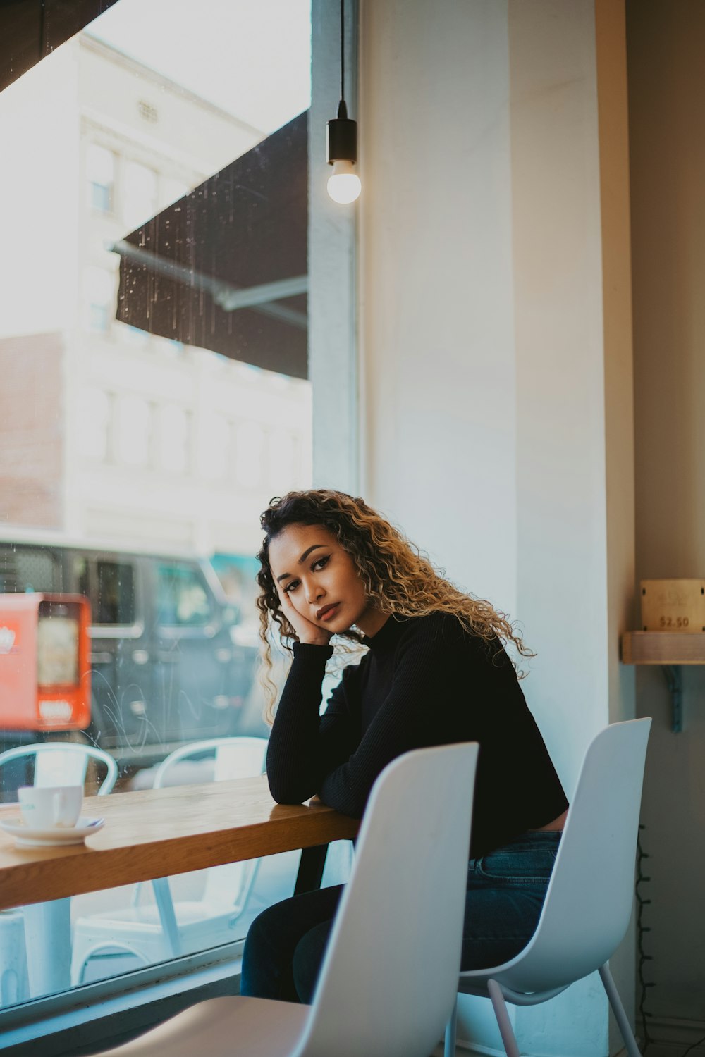 woman leaning on brown wooden table near glass window