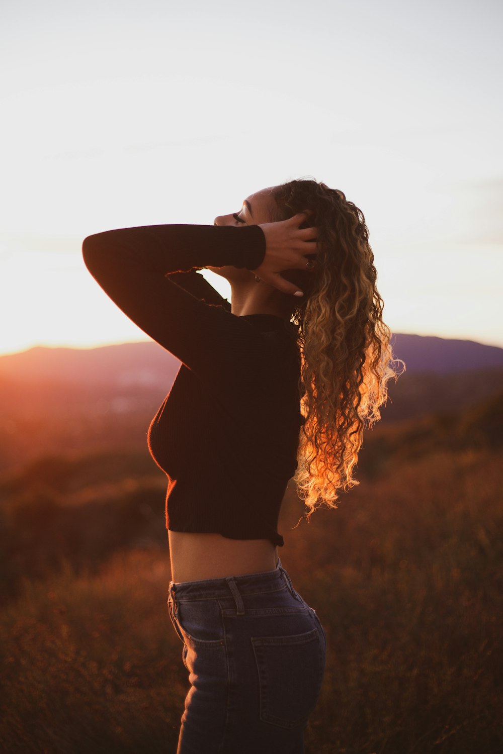 woman standing with both hands touching her hair during day