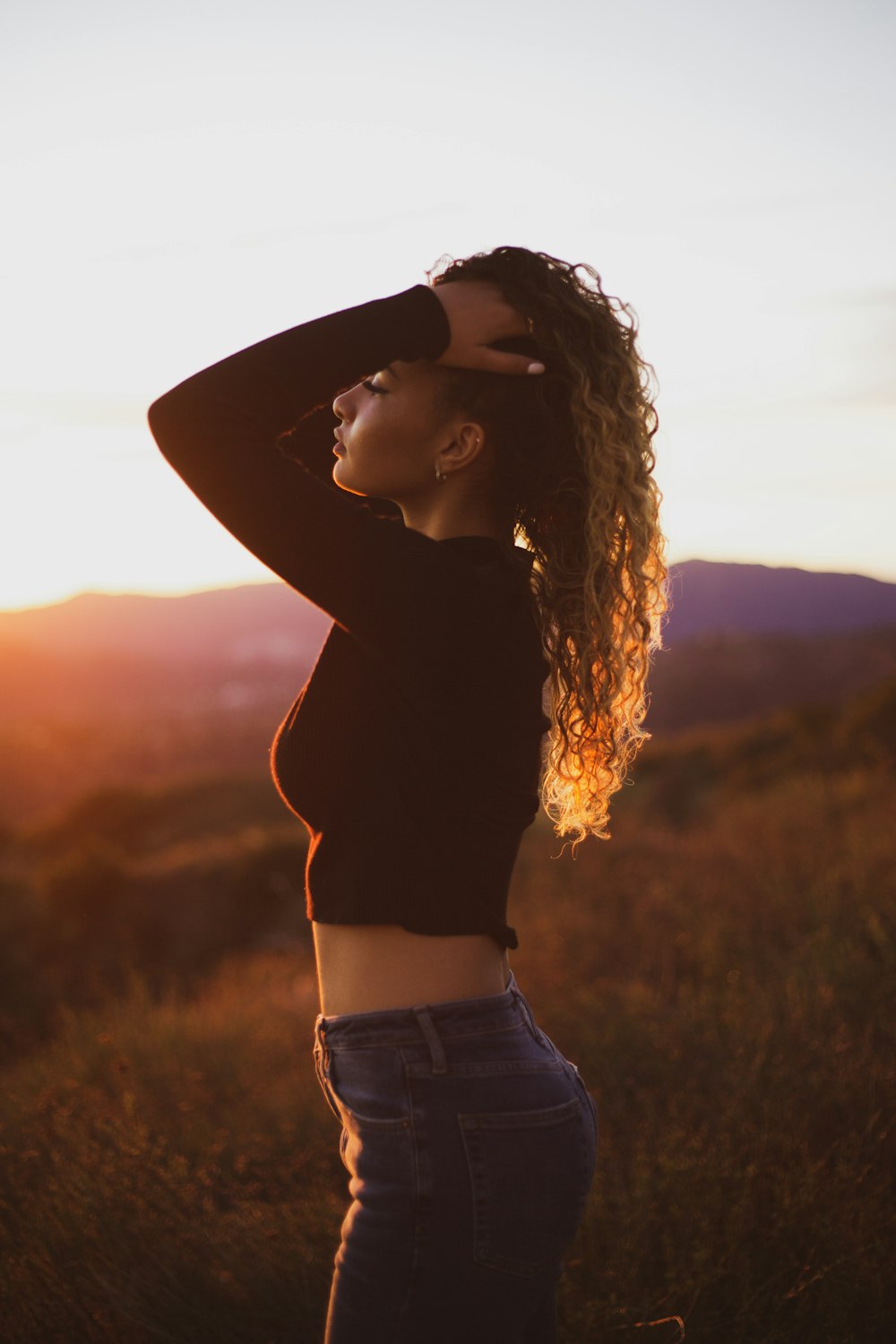 woman standing on field with both hands on head