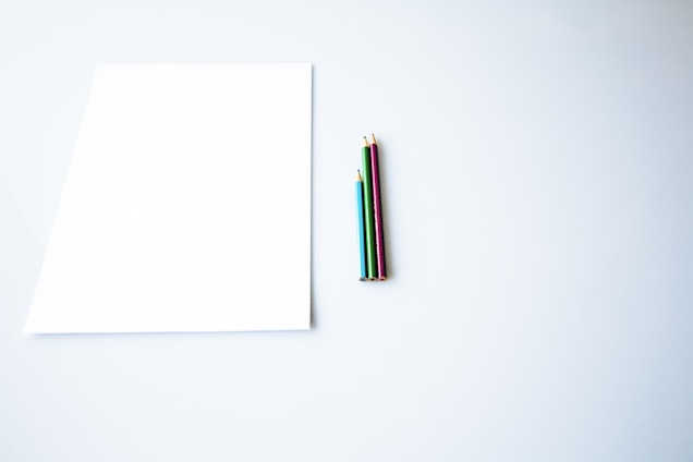 three assorted-color pencils beside paper
