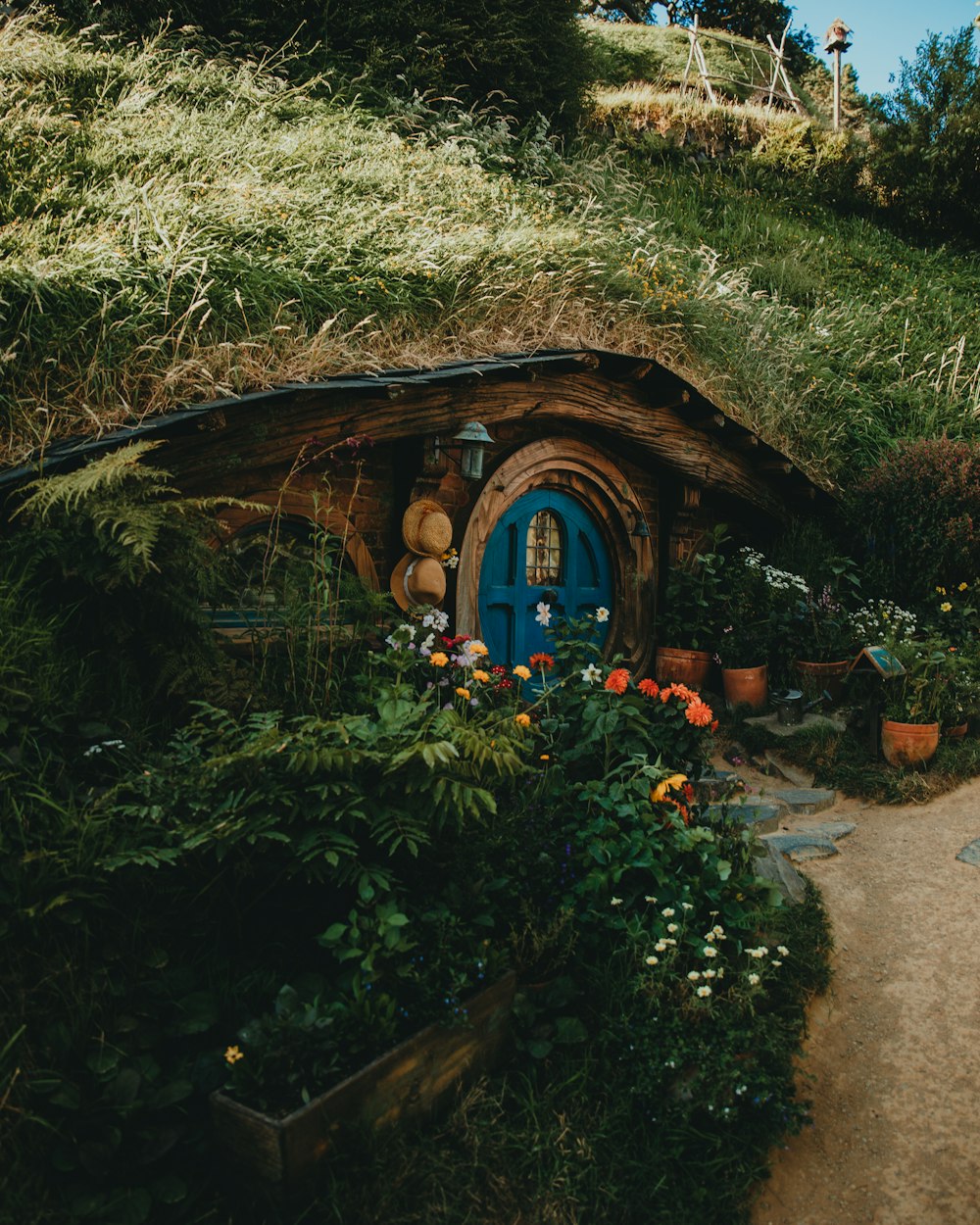 Una casa di hobbot con una porta blu circondata da fiori