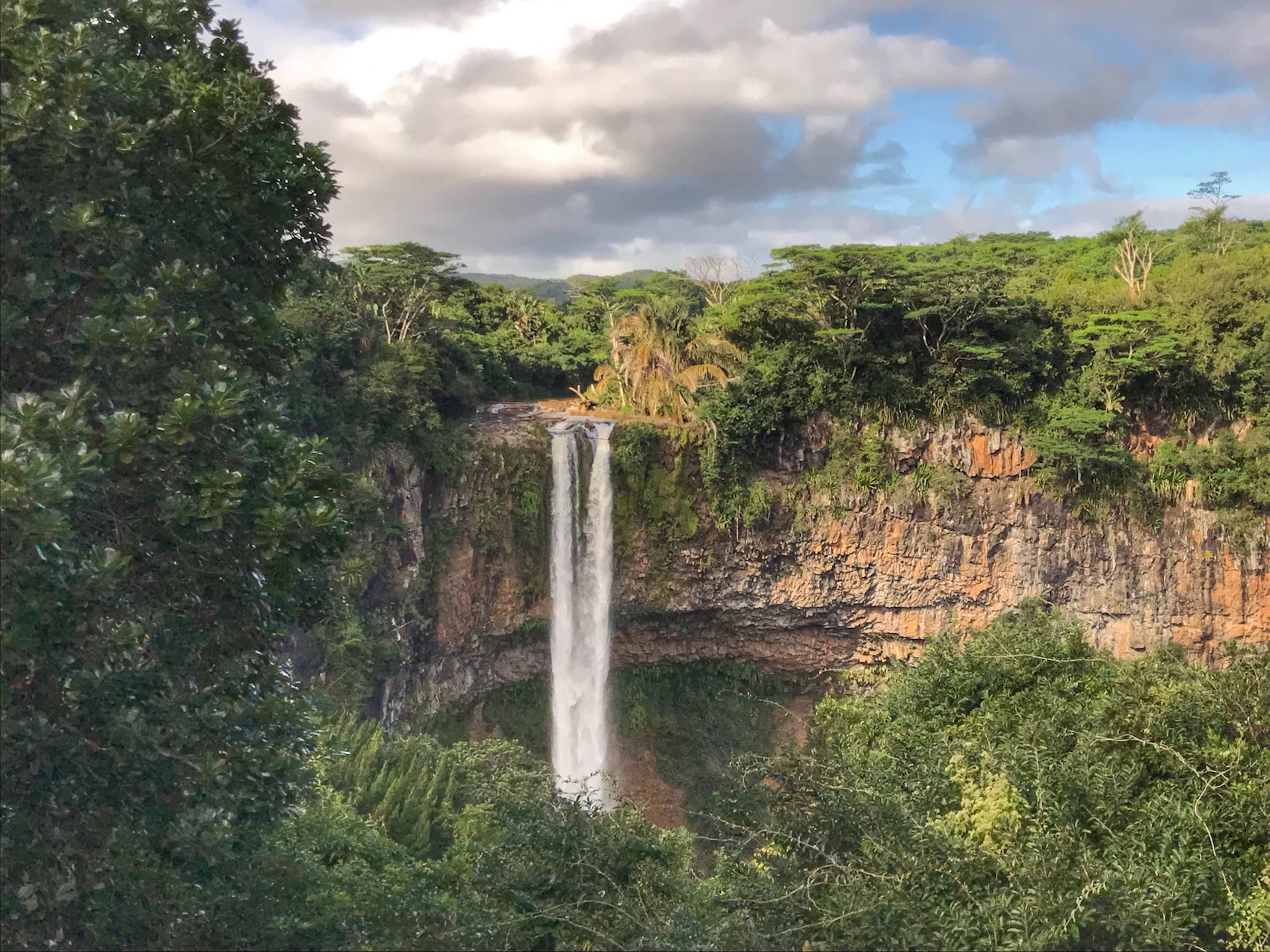 A tall waterfall dropping through dense green forest in Mauritius