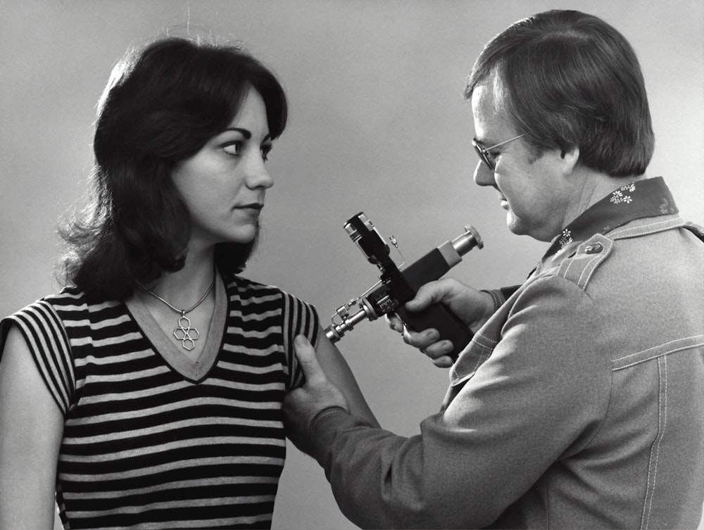 a woman is holding a microscope and a man is looking at it