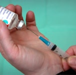 person holding syringe and vial
