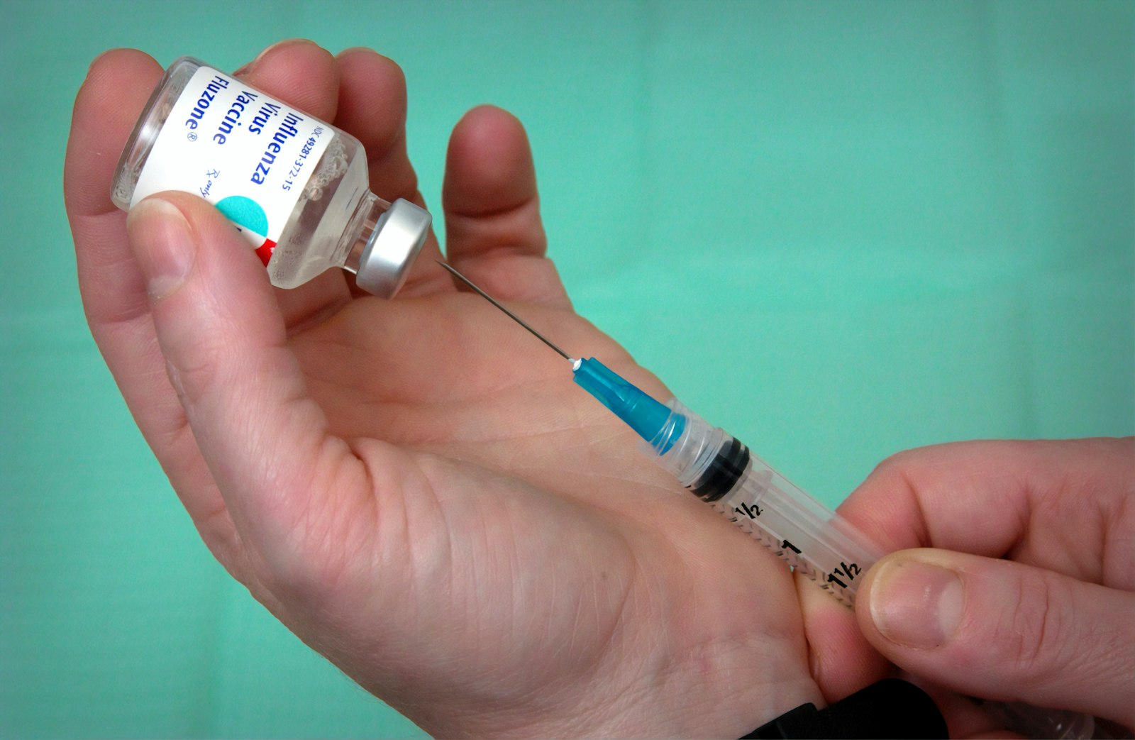 A clinician drawing liquid from a small vial into a syringe, the reconstitution and measuring step this chart describes