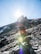 Man hiking in bright sunlight wearing polarized sunglasses with a scenic mountain background.