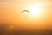 persona sobrevolando en paracaídas con cielo dorado