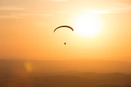persona sobrevolando en paracaídas con cielo dorado