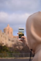 person taking photo of building during daytime