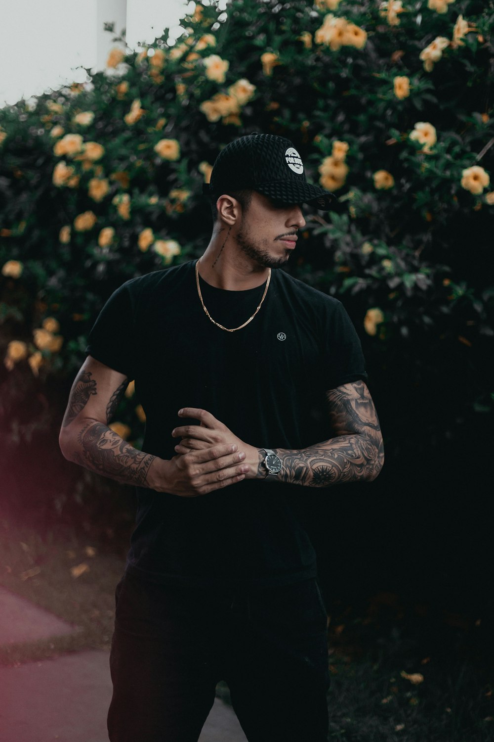 man in black shirt and black pants standing near yellow petaled flowers