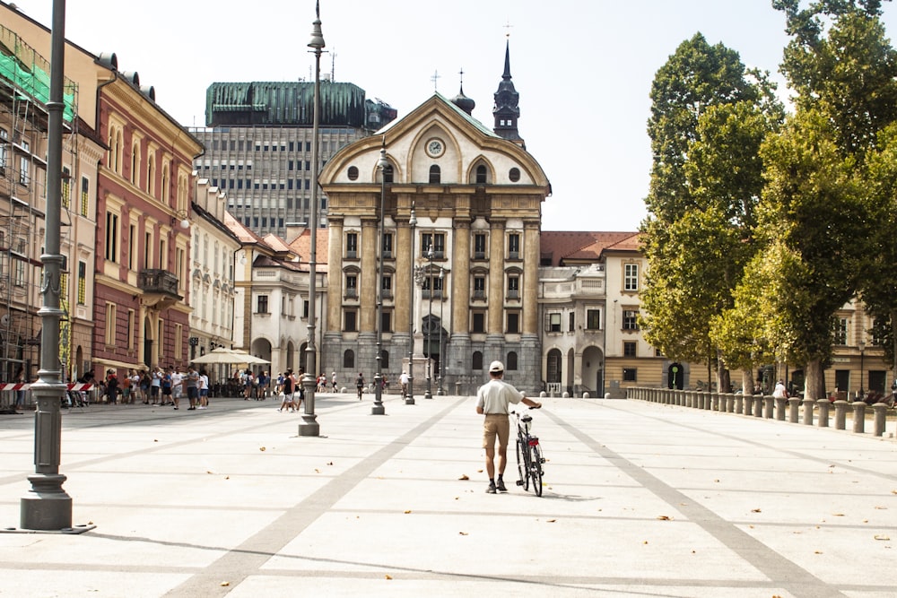 Persona in piedi accanto alla bicicletta davanti agli edifici durante il giorno