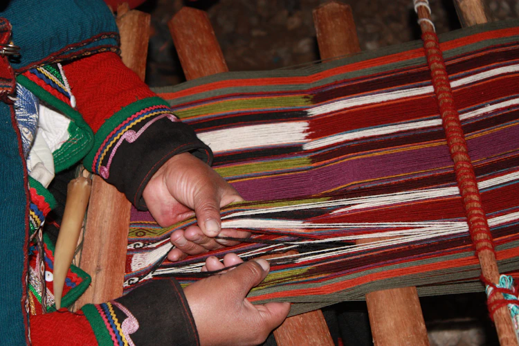 Indigenous hands weaving colorful textile on a traditional backstrap loom