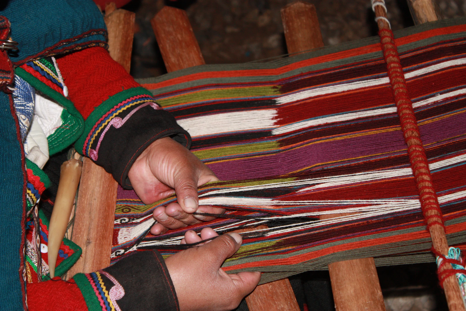 Andean woman weaving colorful traditional textiles on a loom