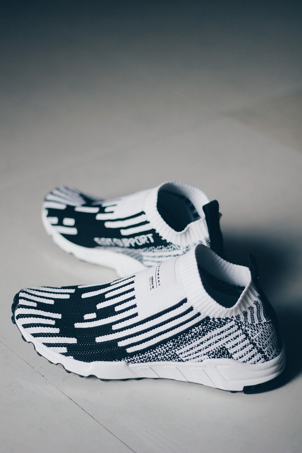 shallow focus photo of pair of white-and-black running shoes