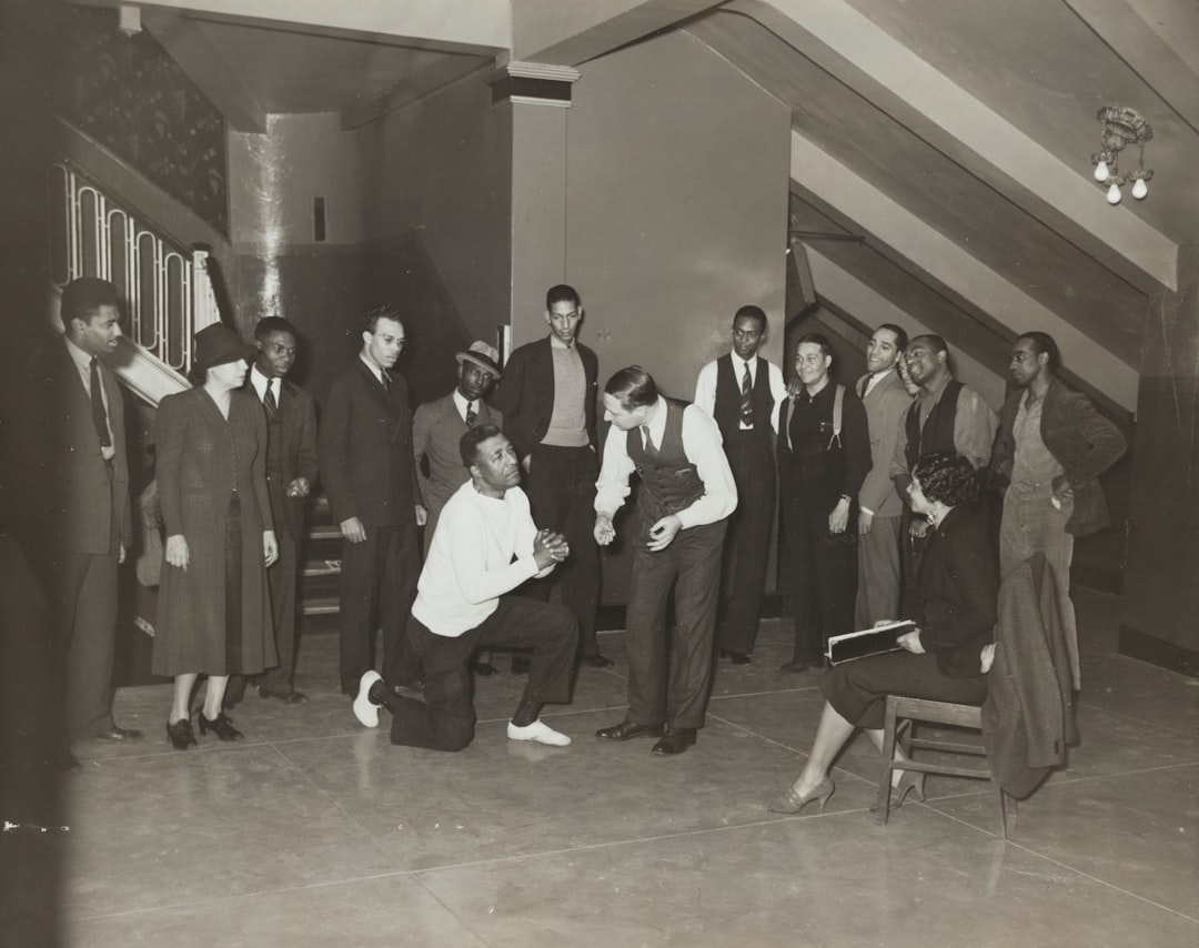 woman sitting and facing man taking a knee beside standing men and women indoors, Rehearsal in Harlem 1935
