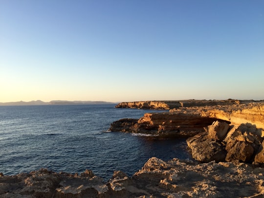 rocky cliff facing ocean under blue sky in Formentera Spain