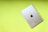A silver iPad with the Apple logo on the back rests on a bright lime green background. The iPad is positioned diagonally, showcasing its sleek metallic design and minimalistic aesthetic.