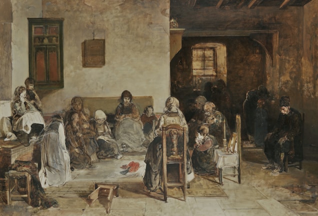 A group of people gather in a dimly lit room, each occupied with their own activities. The setting appears to be rustic, with wooden elements and subdued lighting. The central figure is seated on a chair facing the viewer, surrounded by others; some are sitting against the walls, while others are huddled together, conveying a sense of community or shared experience.