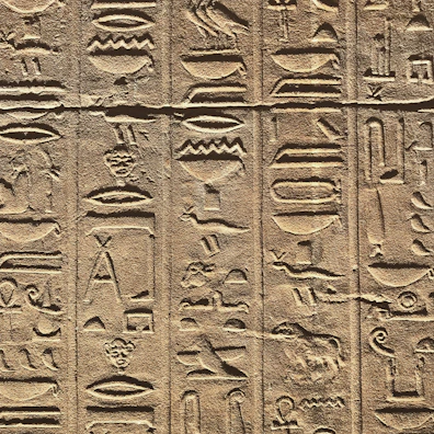 A close-up of intricate hieroglyphs carved into an Egyptian megalith at sunrise.