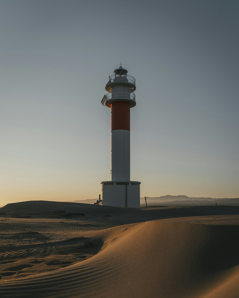 white and red lighthouse on desert