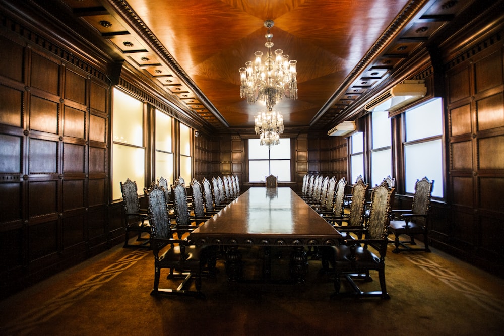 rectangular brown wooden long table inside building and lighted crystal chandelier