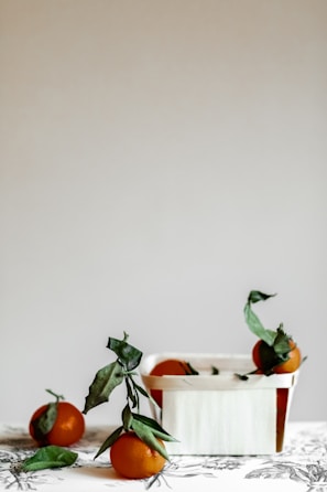 A minimalist modern display of assorted fresh tropical fruits in a wooden crate.
