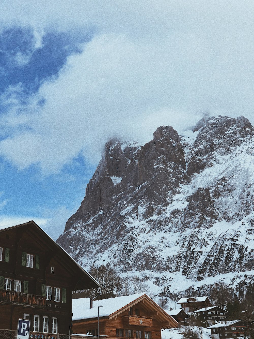 casas e cume da montanha coberto de neve sob o céu branco e azul